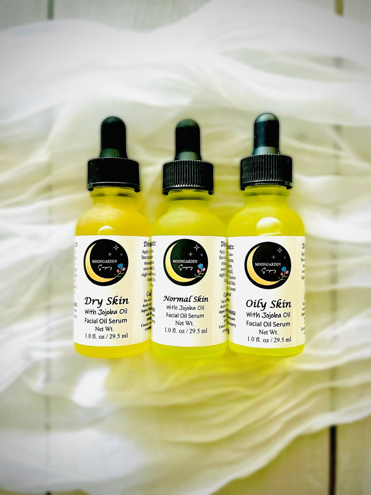 Three small bottles of facial oils on a cheesecloth.