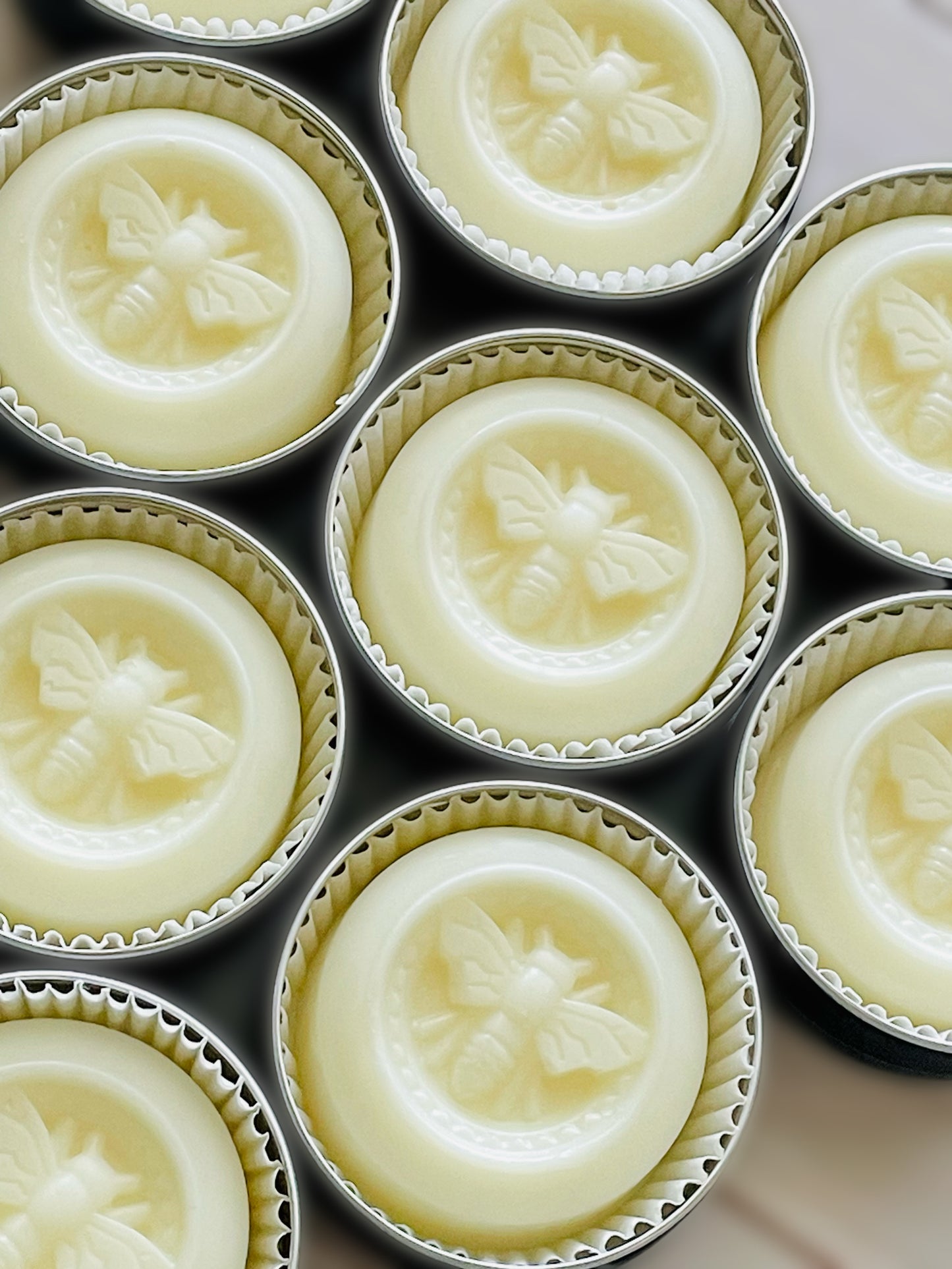 Several round opened tin jars showing solid lotion bars.
