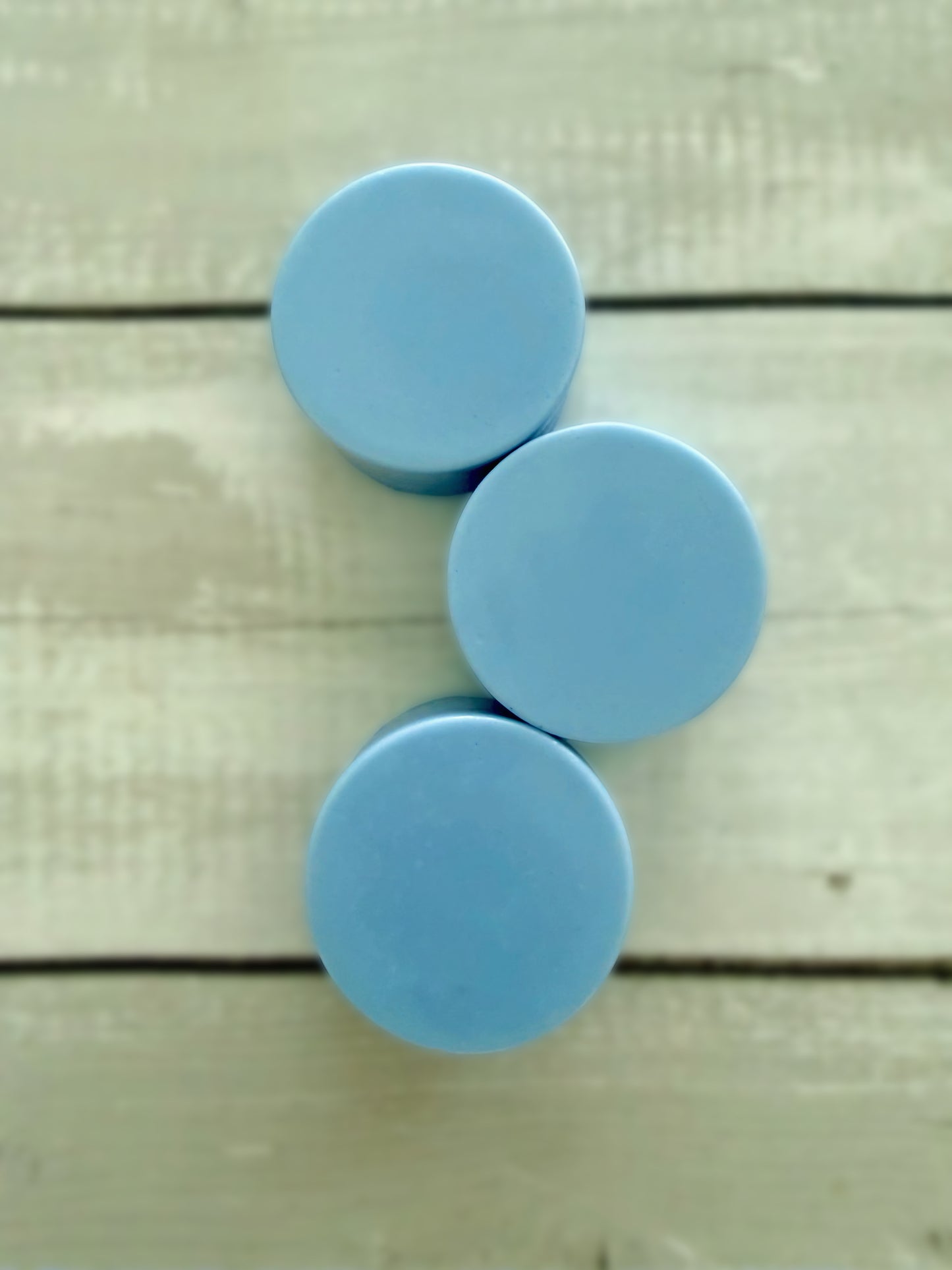 Three blue solid conditioner bars, arranged on a rustic wooden background.