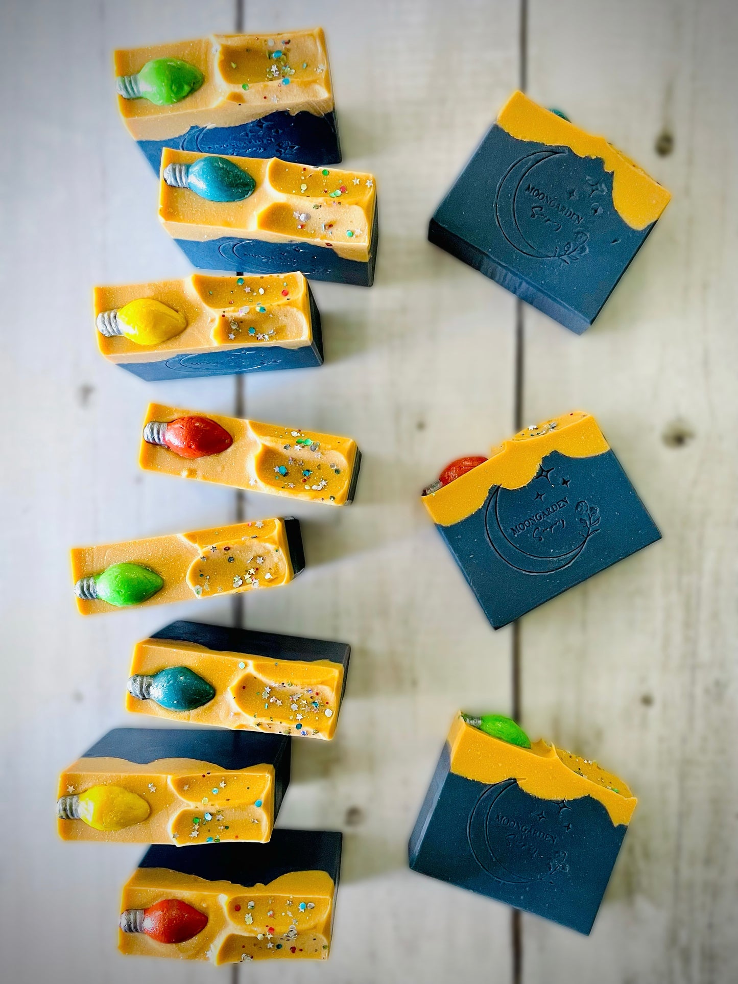 Eleven bars of handmade soap with a Christmas light soap embed on top.