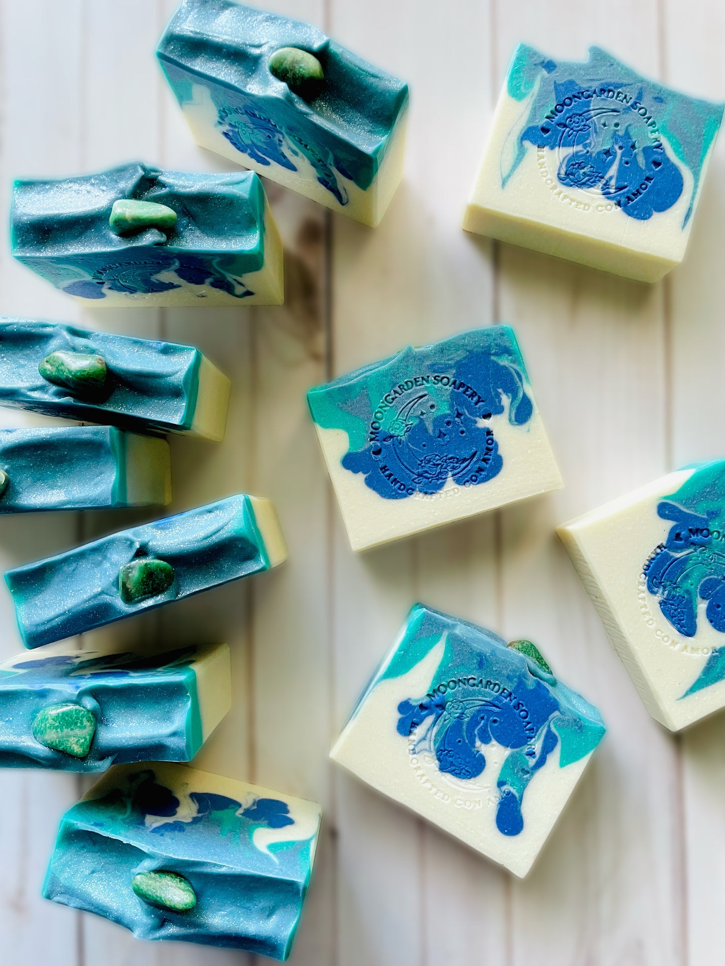 Eleven bars of handmade soap with a green quartz stone on top.