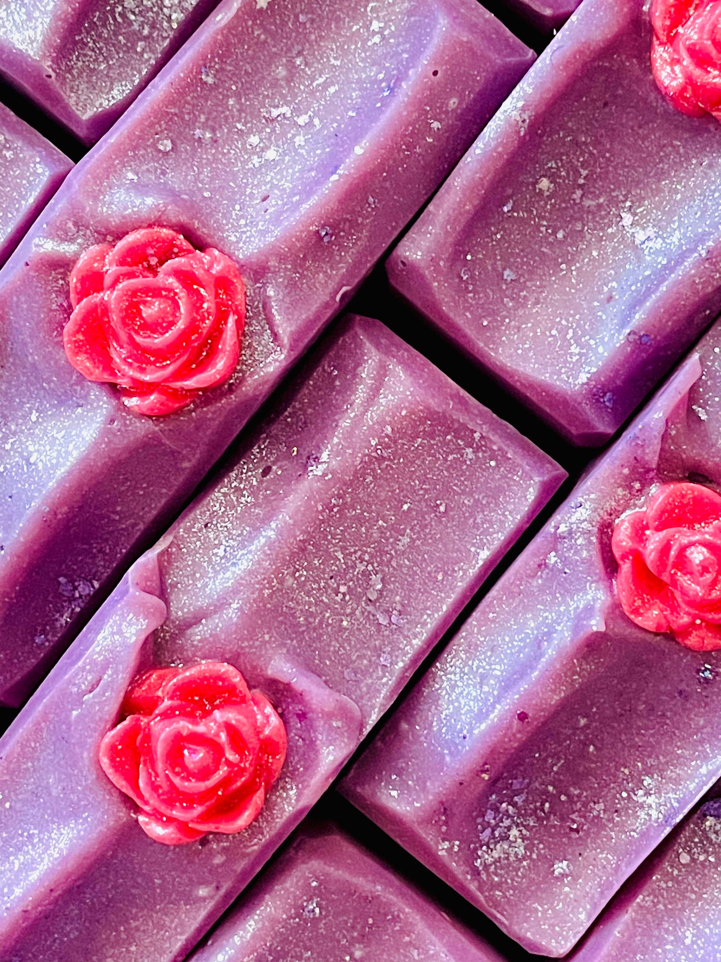 A closeup of the tops of La Reina bar soaps. Each soap as a rose soap dough embed on top.