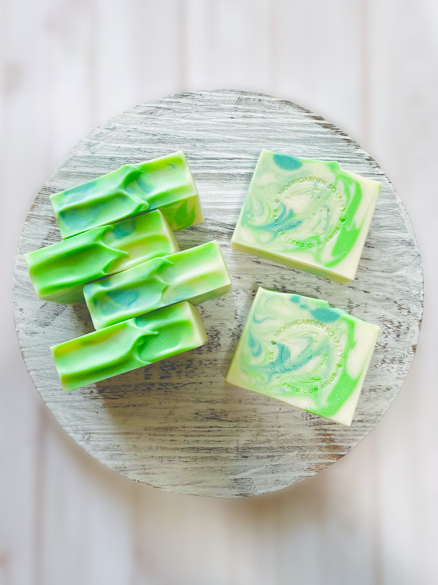 Six soap bars on top of a round wooden serving tray.