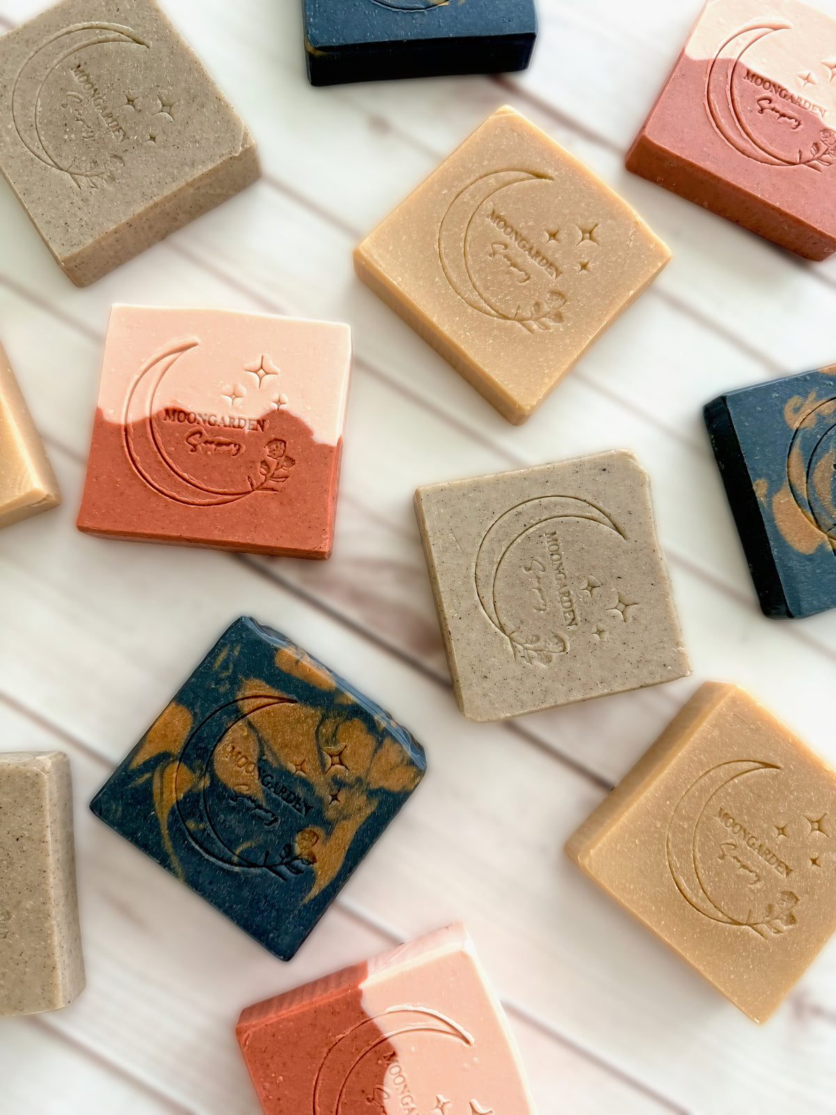 Various facial soap bars arranged on a white rustic wooden background. 