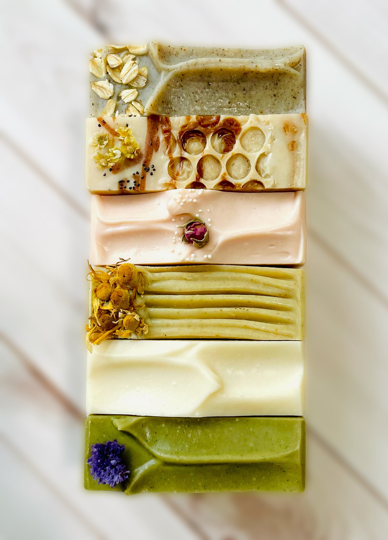 Six bars of soap lined up on top of photo backdrop.