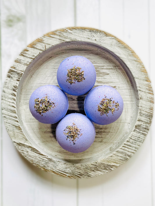 Four bath bombs on a round wooden serving tray. 