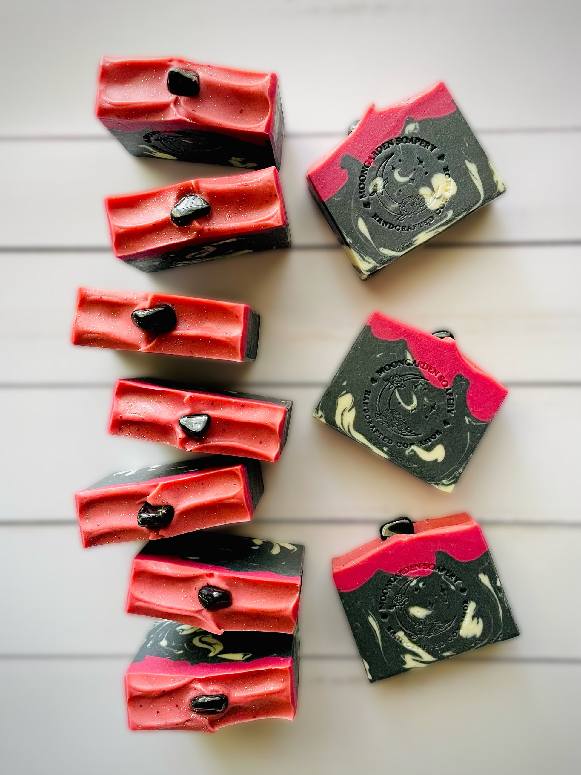 Ten handmade bars of soap. Each soap has one black onyx stone on top.  