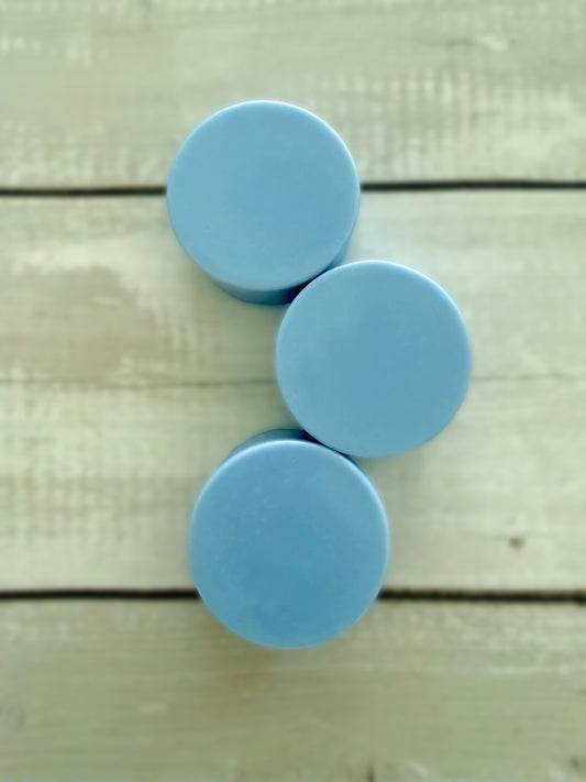 Three blue solid conditioner bars, arranged on a rustic wooden background. 