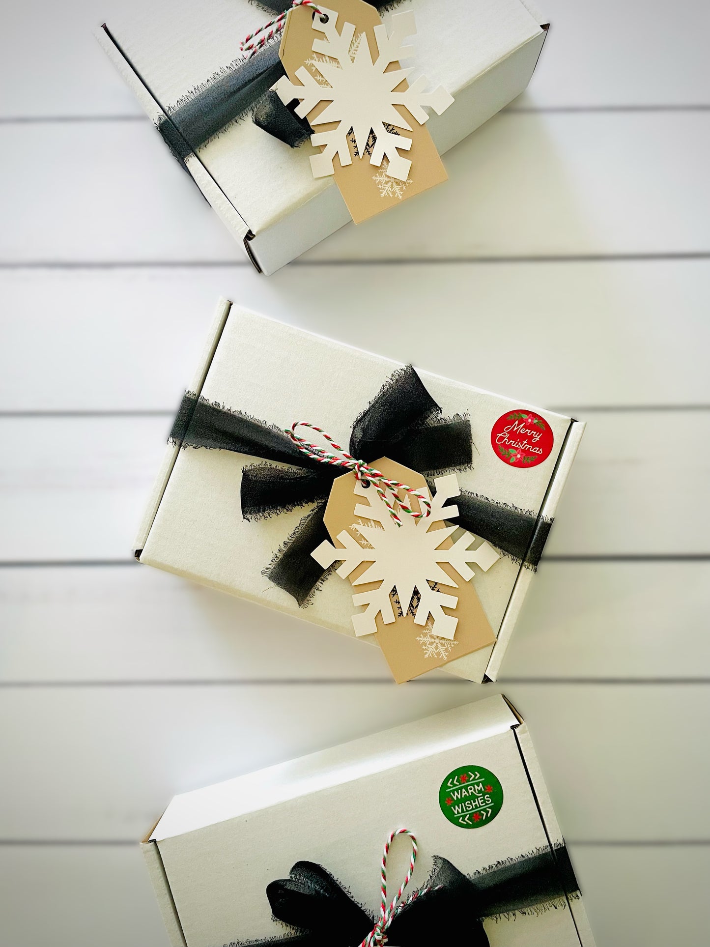 Three holiday gift boxes with chiffon ribbon and snowflake tag. 