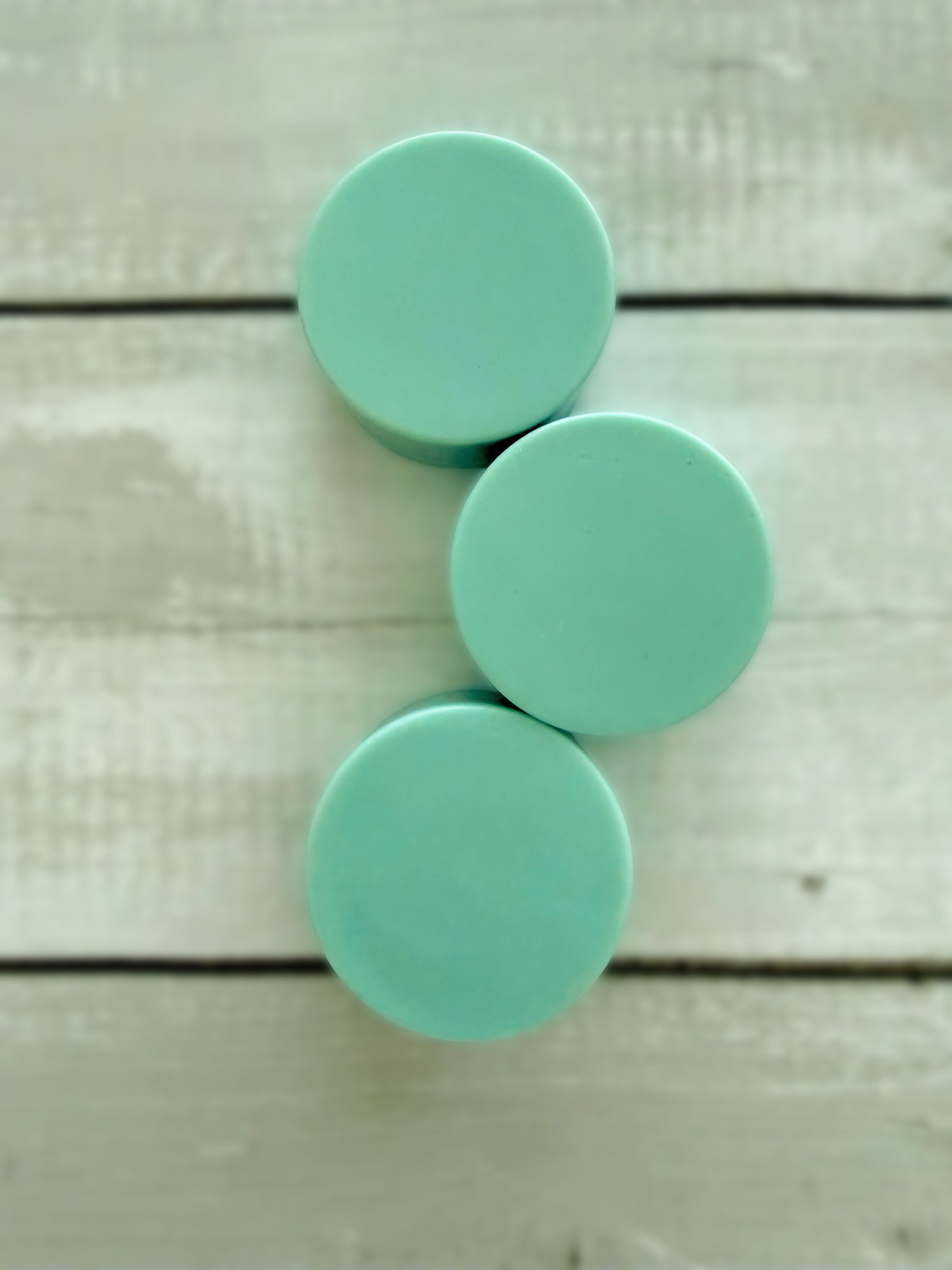 Three green solid conditioner bars, arranged on a rustic wooden background. 