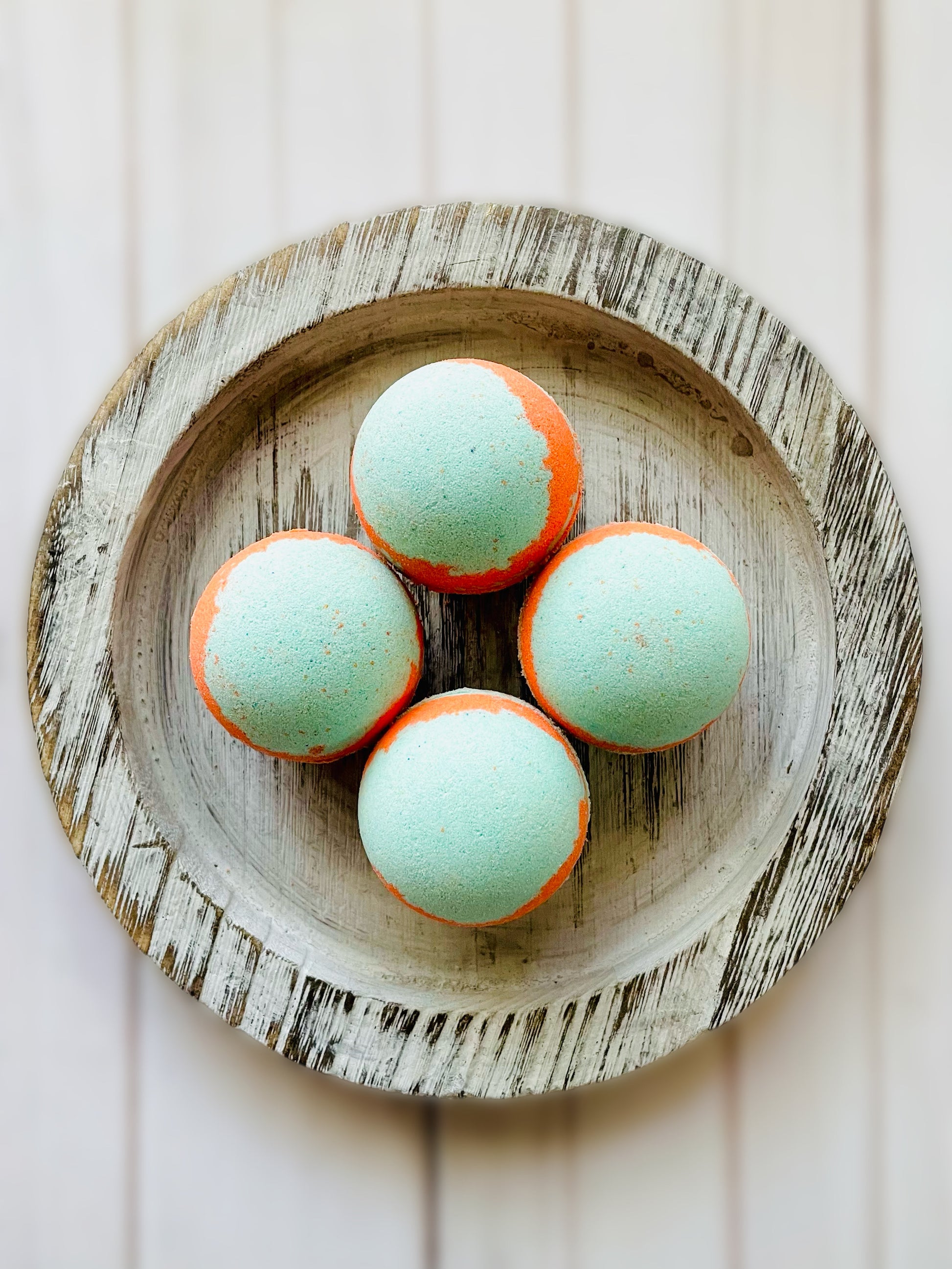 Four bath bombs on a round wooden serving tray. 