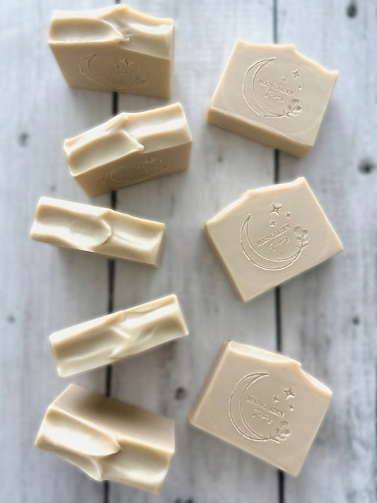 Nine white handmade soap bars, arranged on a white rustic wooden background. 