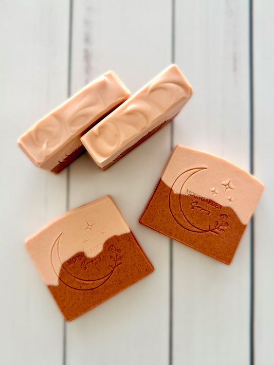 Four handmade facial soap bars in rose clay and calamine, arranged on a white rustic wooden background. 