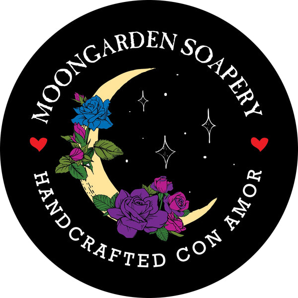 The business logo is circular, and it has a phrase on top that reads Moongarden Soapery. The bottom phrase reads, handcrafted con amor.  There is a miniature heart on the left and right side of the logo, right in between the first and last letter of each phrase.  The image of the logo contains a crescent moon wrapped in roses and leaves. There are 3-diamond shape stars on the right of the crescent moon with tiny dotted stars around it. 