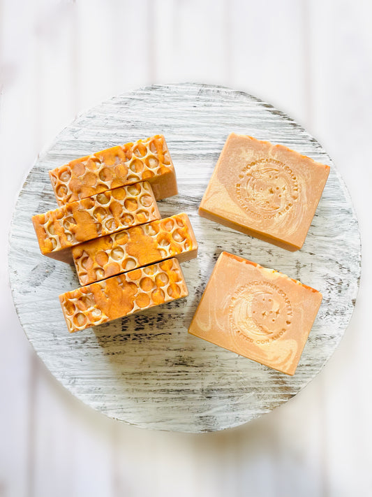 Six soap bars on top of a round wooden serving tray. 