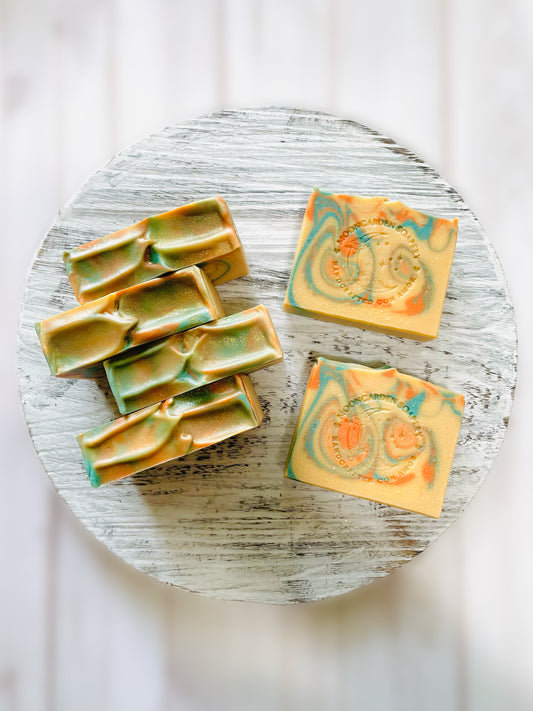 Six soap bars sitting on a round wooden serving tray. 