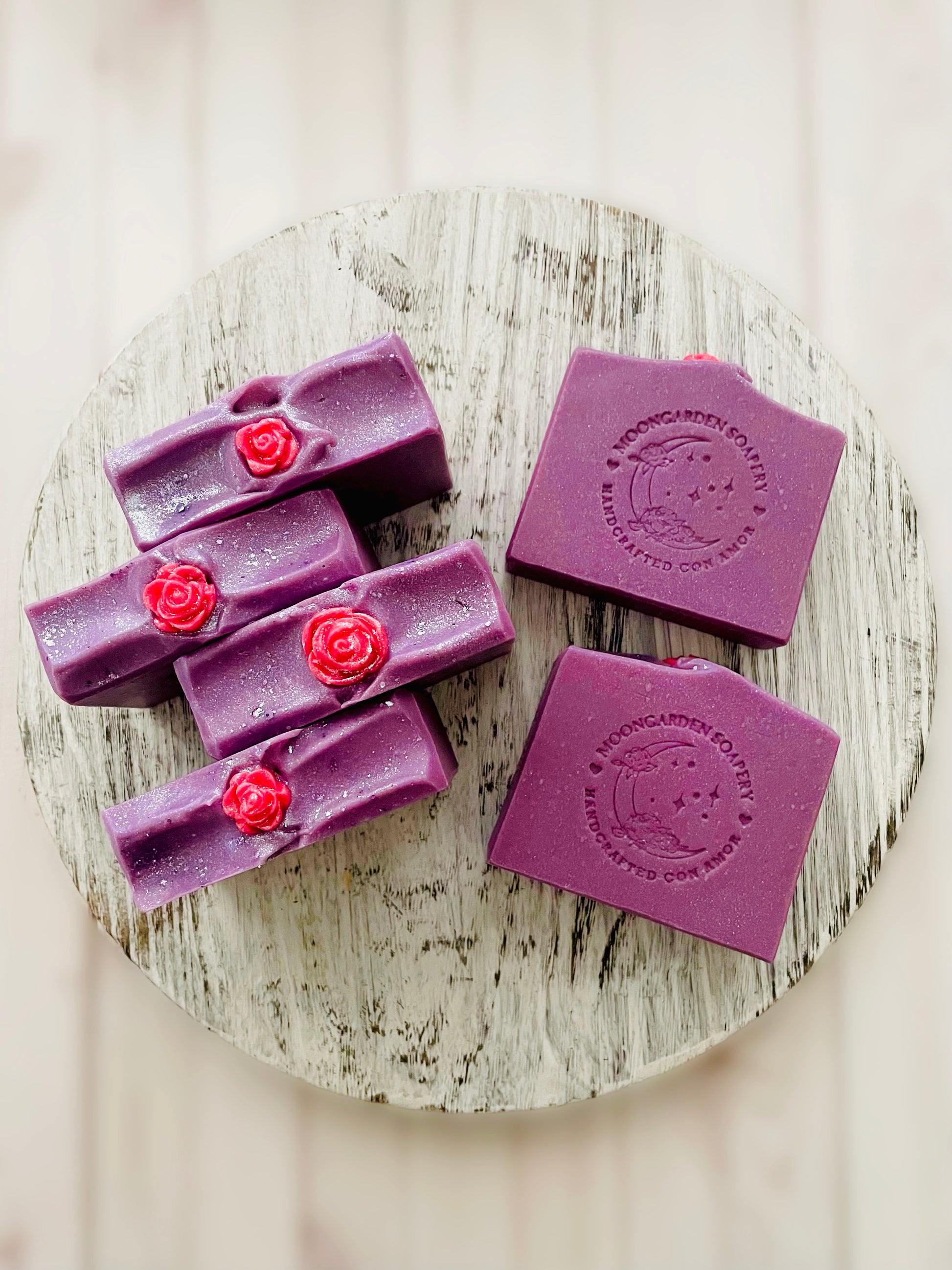 Six soap bars sitting on a round wooden serving tray. 