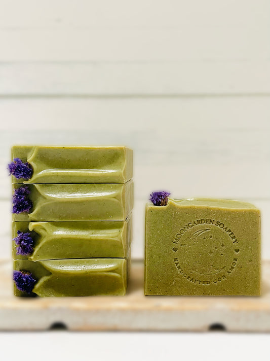 Four Jade soaps stacked on the left and one on the right. All soaps sit on top of a wooden serving tray.   