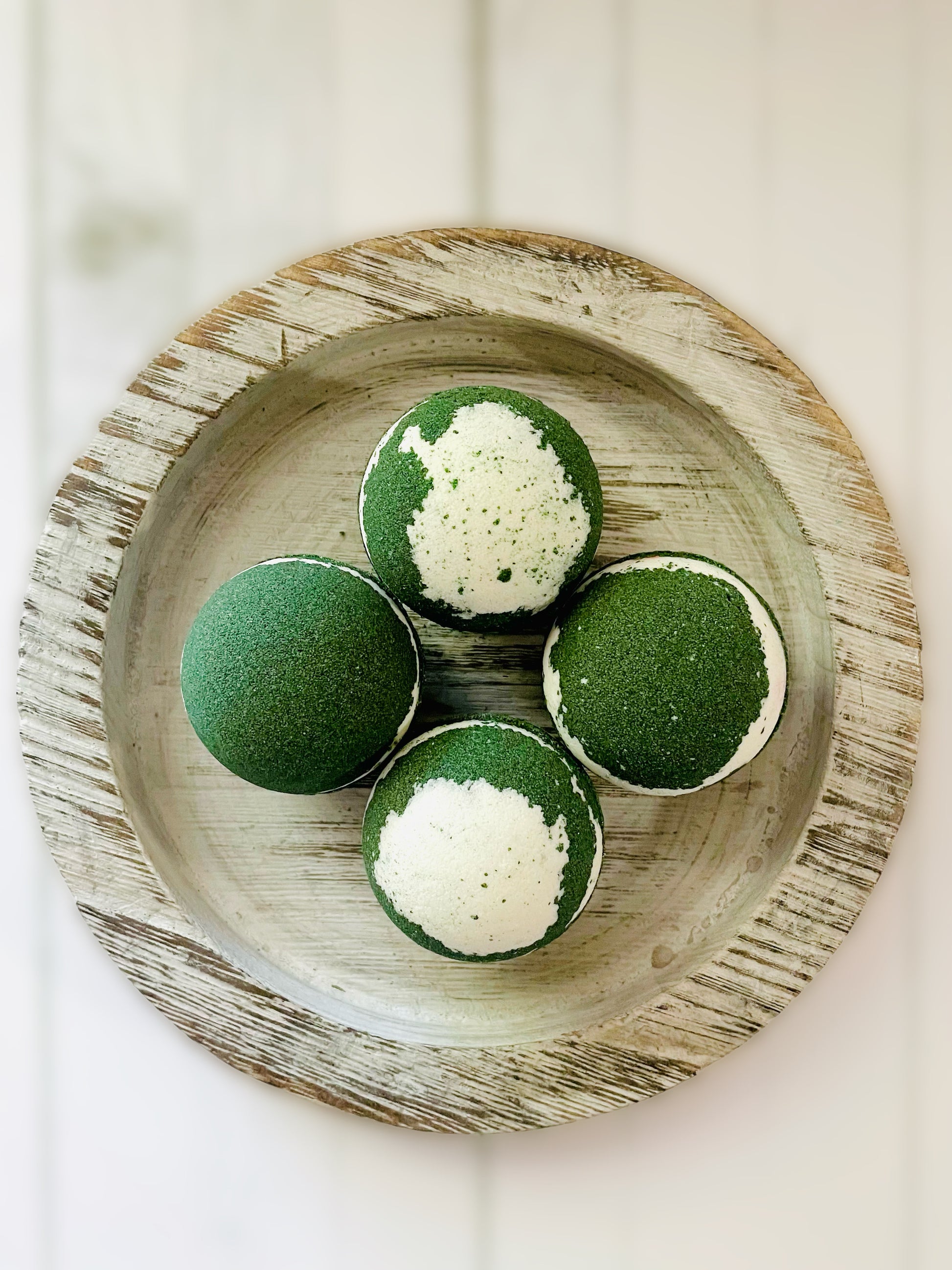 Four eucalyptus and mint bath bombs on a round wooden serving tray. 