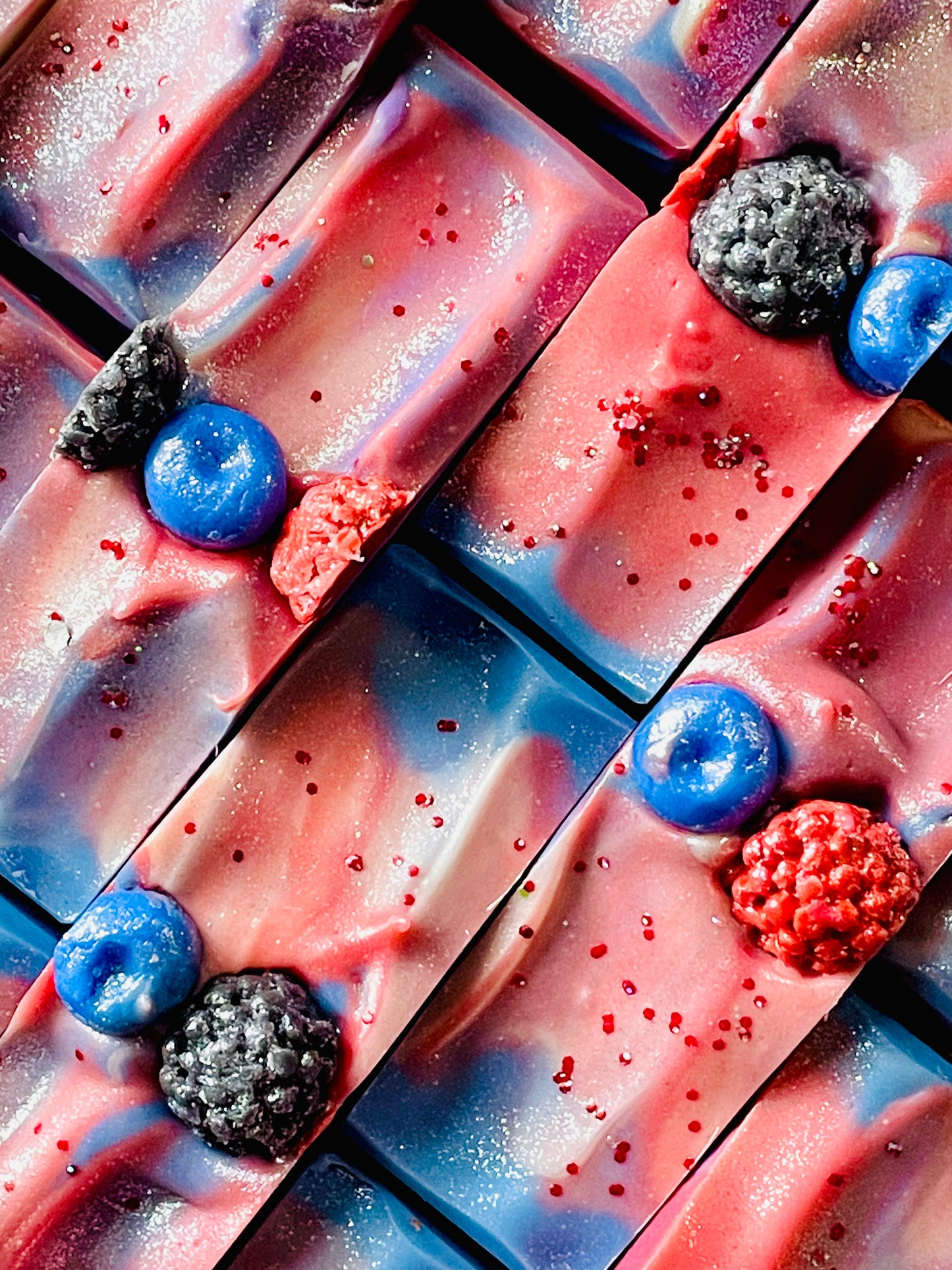 A closeup of the tops of Chiquilla bar soaps. Each soap has blueberry, blackberry, and raspberry soap dough embeds.p