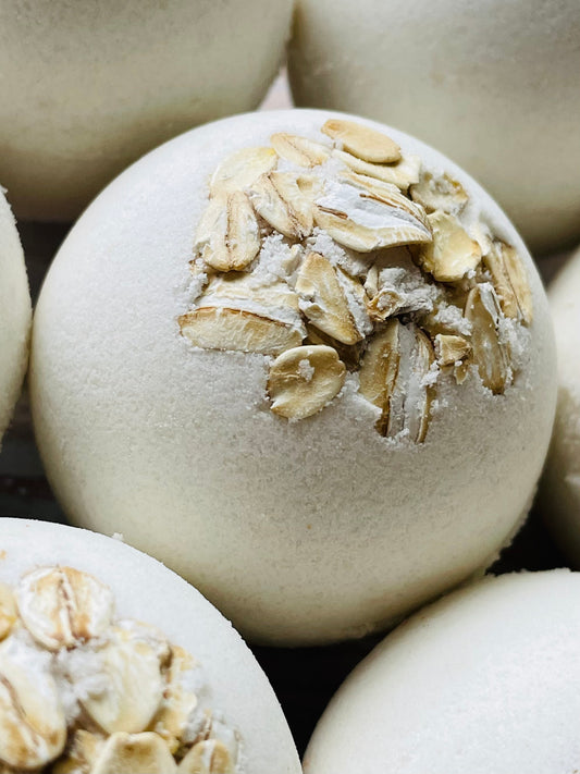A closeup of oatmeal, milk and honey bath bombs topped with whole oats.
