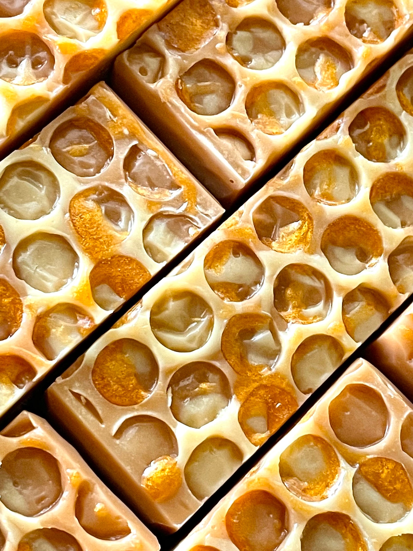 A closeup of the tops of Honey Pot honey bar soaps.  Each bar has a honeycomb imprint and honey soap drizzle on top. 