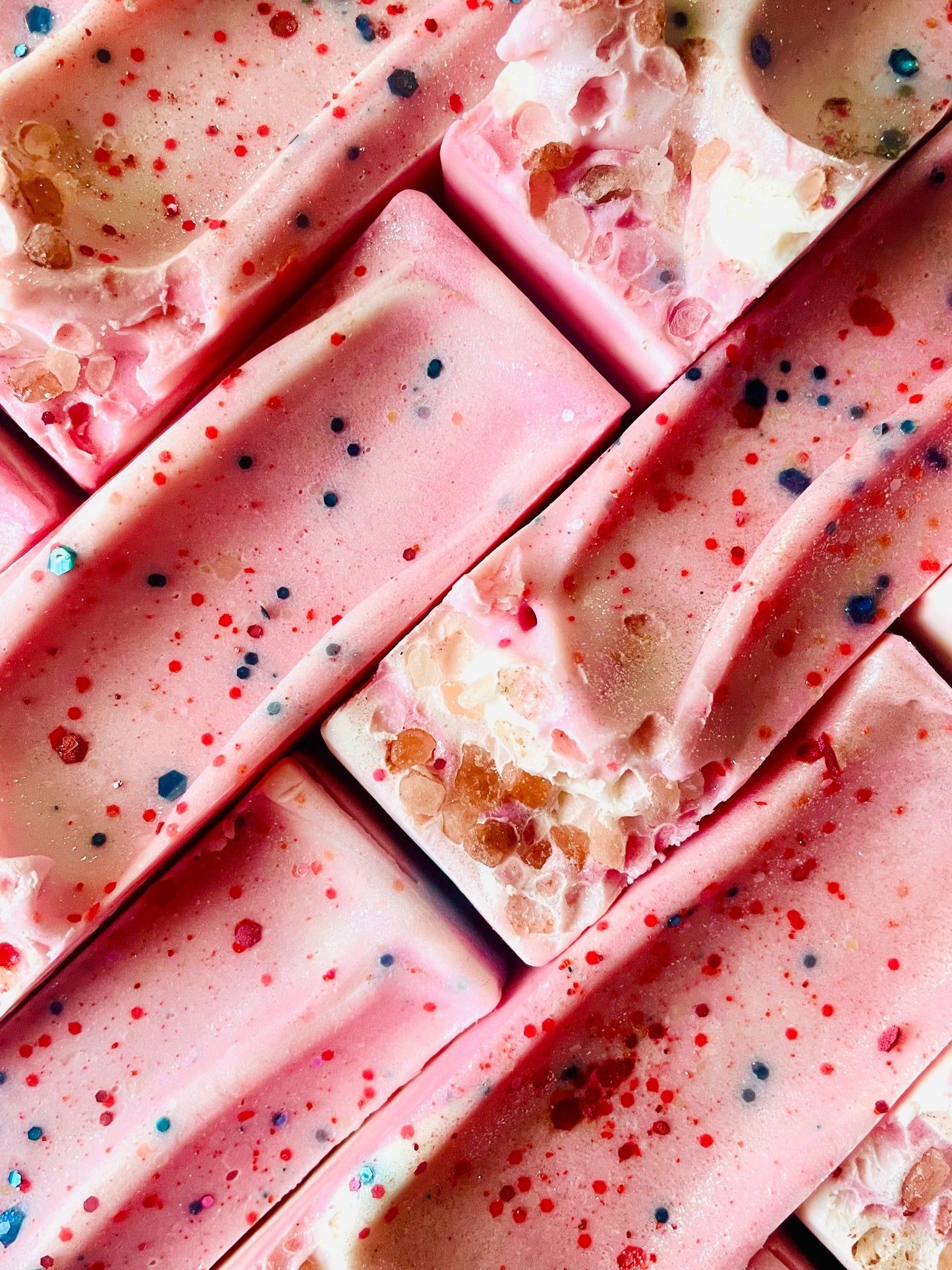 A closeup of the tops of Forever Young bar soaps. Each bar has pink Himalayan sea salt and glitter on top.