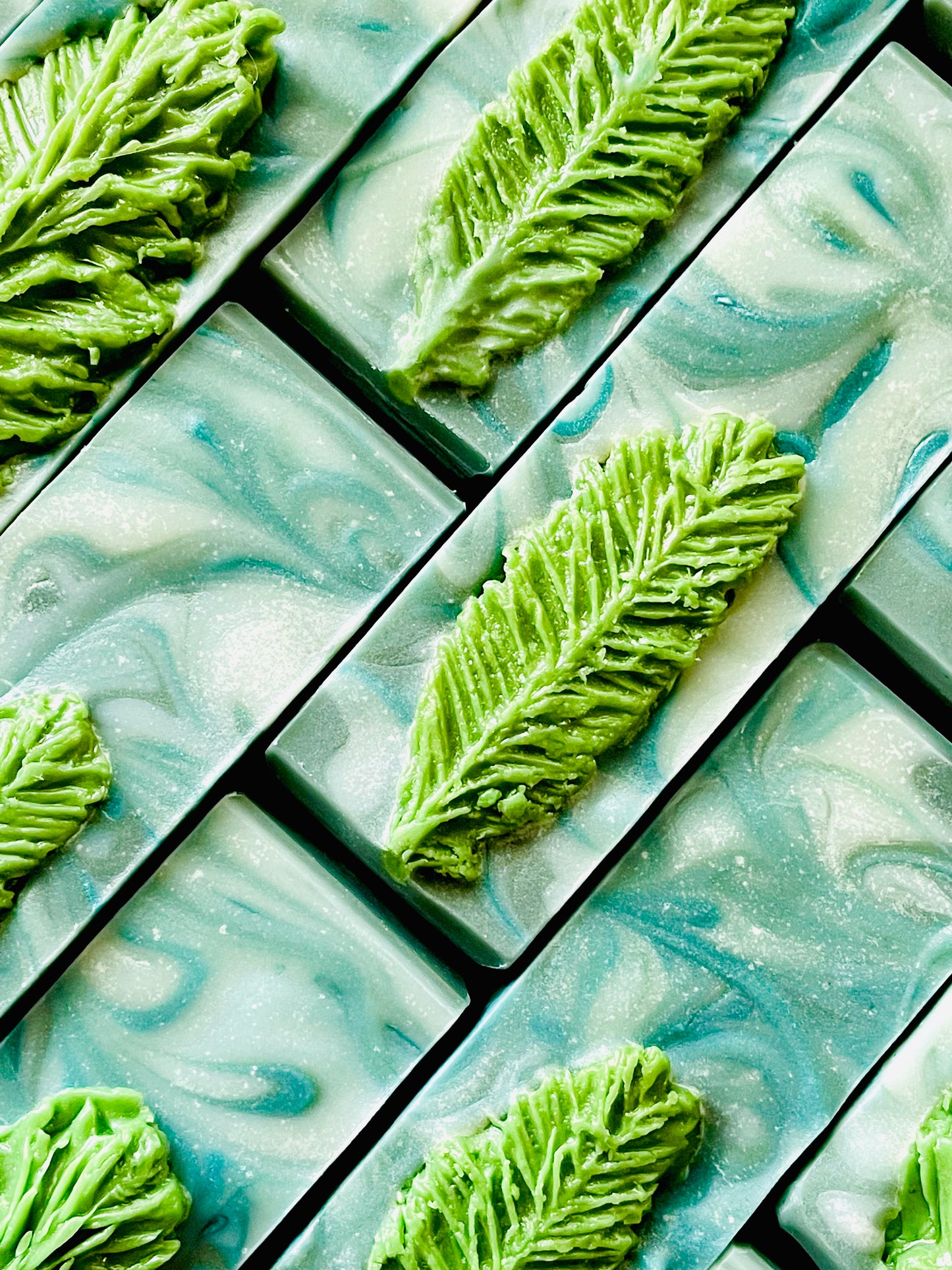 A closeup of the tops of Forest of Illusion bar soaps. Each bar has pine tree needle soap dough embed on top.