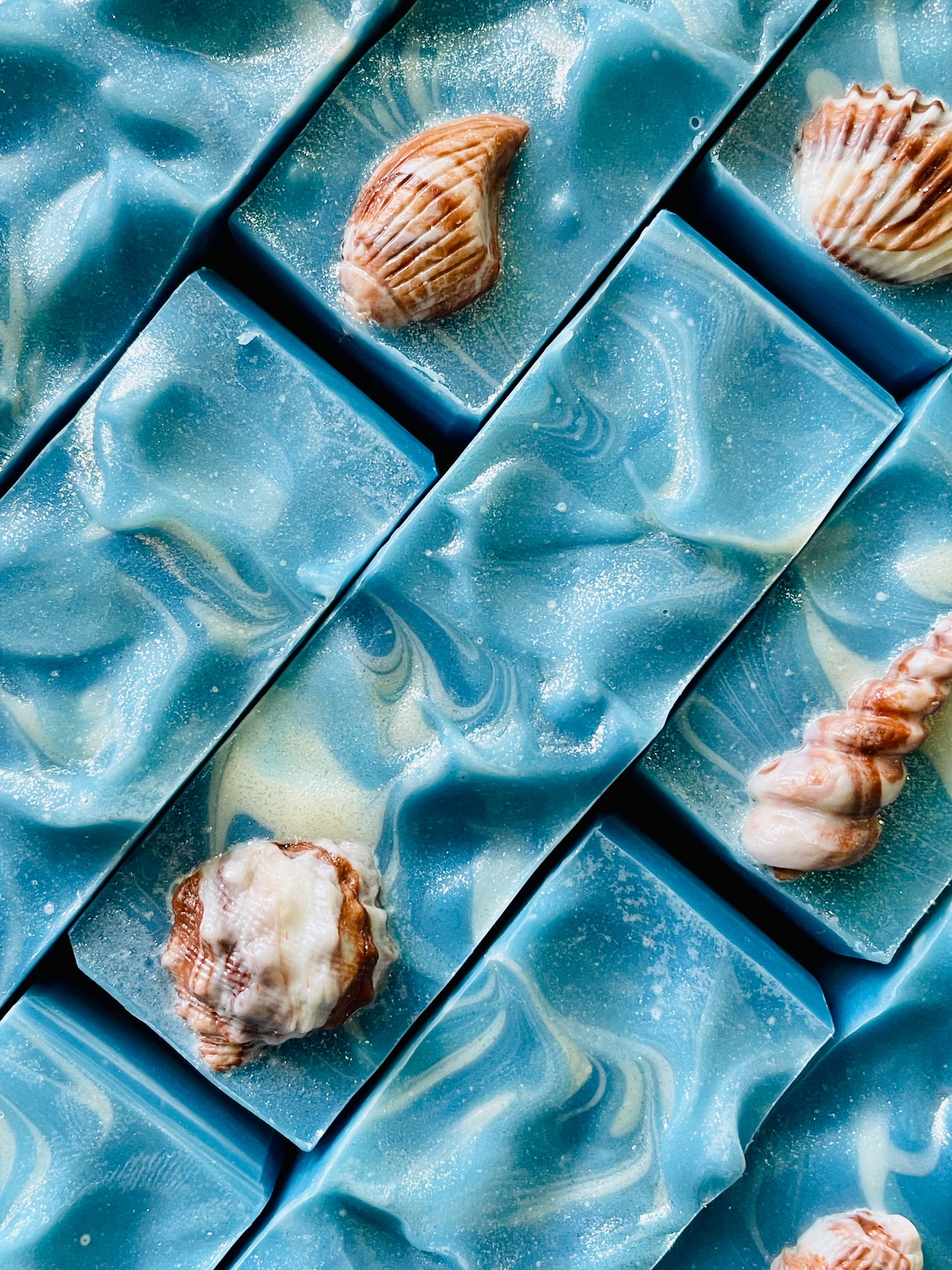 A closeup of the tops of Playa bar soaps. Each bar has a shell soap dough embed on top.