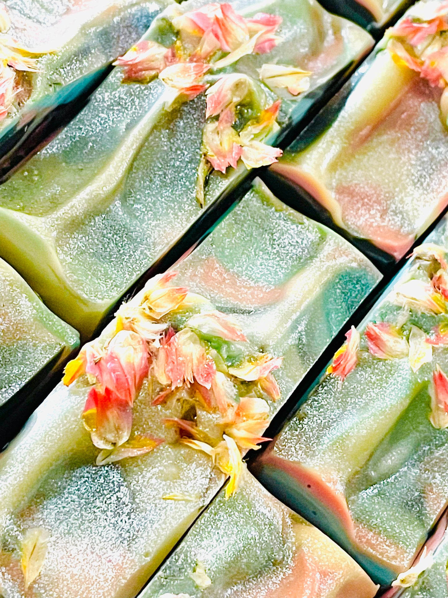 A closeup of the tops of Lady Georgiana bar soaps. Each bar has dried flowers and glitter on top.